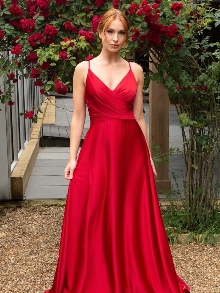Bridesmaid in a red satin wrap-bodice gown among rose blooms